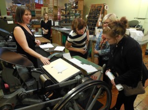 Ladies captivated by ancient letterpress machines.