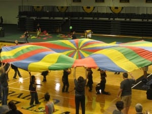 Playing with a parachute is a colorful way to learn teamwork and athletics.
